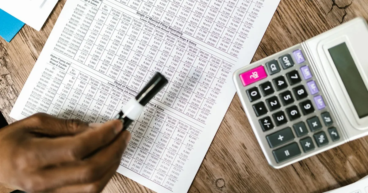 Pessoa organizando contas e calculadora para renegociar dívidas financeiras - HotMoney